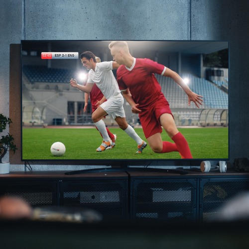 black couple watches professional soccer match on tv sitting on a couch at home